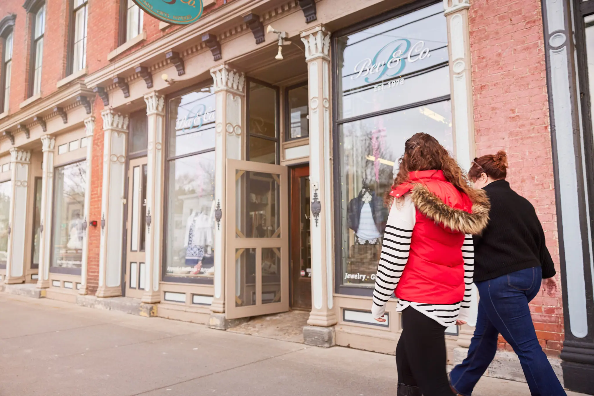two women walking in front of retail building