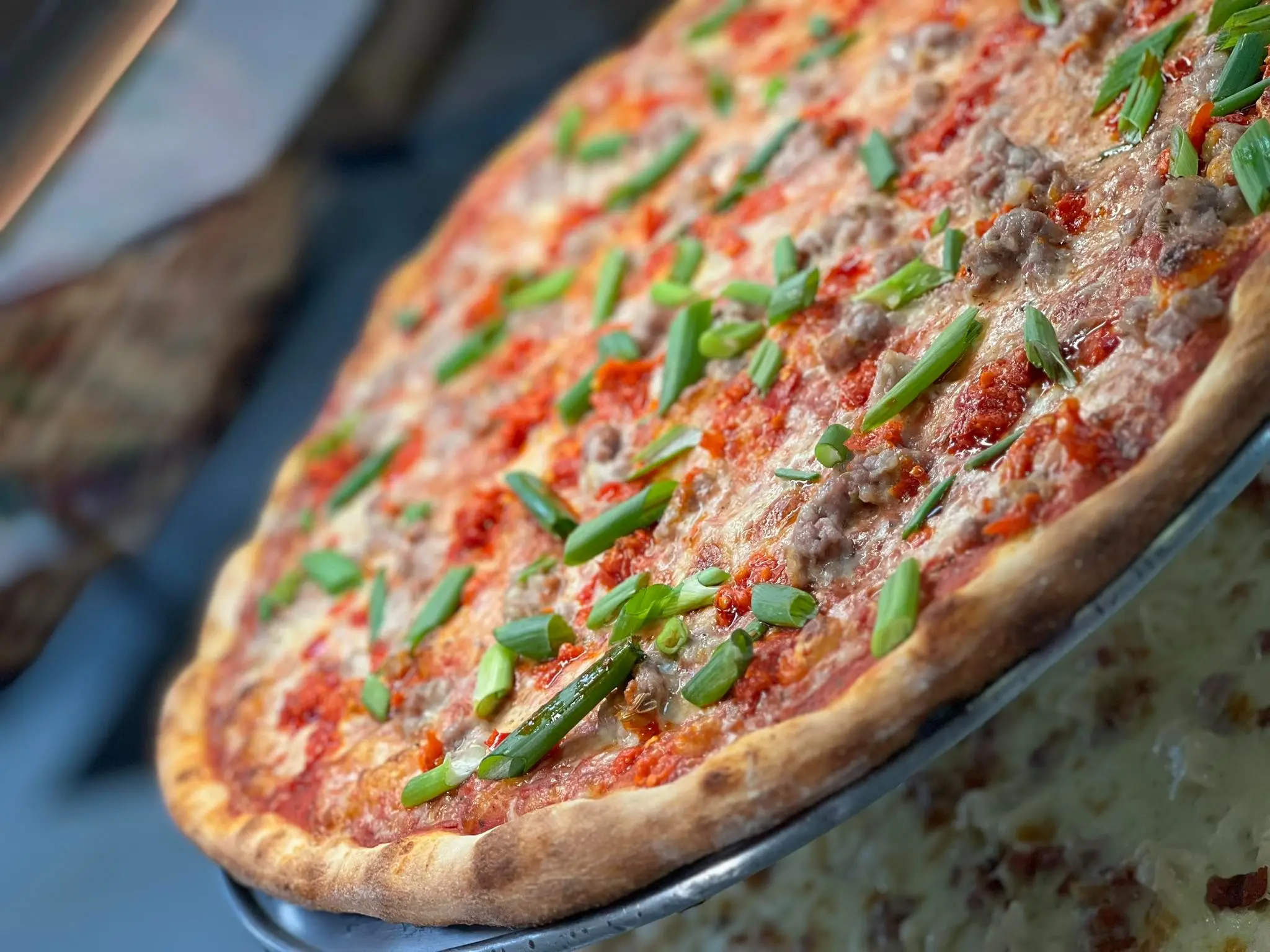 A large pizza topped with various ingredients on a round metal pan.